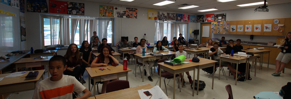 Grade 8 students sitting in desks in a classroom.